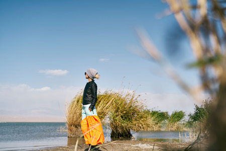 asian woman tourist standing by a lake looking at view under blue sky