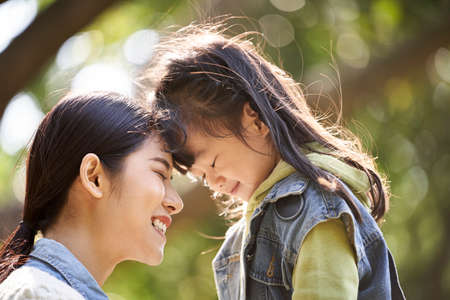 young asian mother and daughter enjoying a good time outdoors in city parkの写真素材