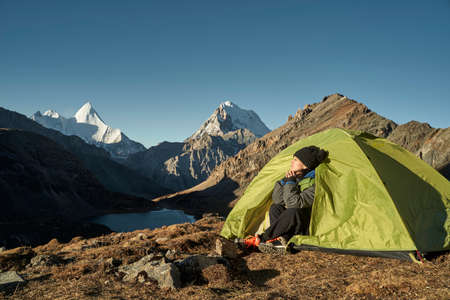 asian woman female camper sitting in tent enjoying the early morning sunlight with eyes closed in yading national park, daocheng county, sichuan province, chinaの写真素材