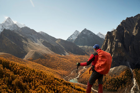 rear view of an asian hiker looking at the river valley in the mountains in yading national park,...