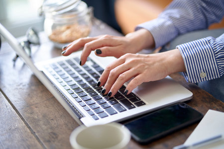 close-up shot of hands and fingers of an asian woman working from home using laptop computer