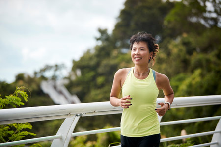 young asian woman running jogging exercising outdoors in city parkの写真素材