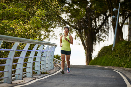 young asian woman running jogging exercising outdoors in city parkの写真素材