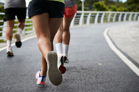 rear view of legs and feet of young asian people running outdoors in parkの写真素材