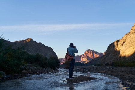 rear view of asian photographer taking photo of sunrise at the Tianshan Mysterious Grand Canyon, Xinjiang, Chinaの写真素材