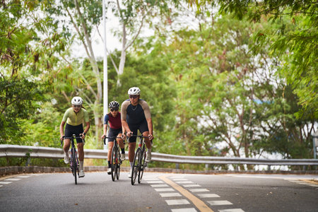 group of three young asian adult cyclists riding bike on rural roadの写真素材