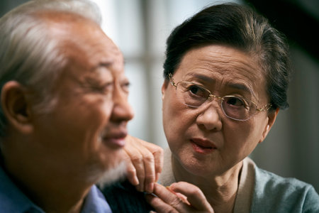 caring senior asian woman looking at husband with concern