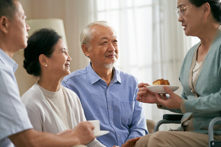 senior asian woman sitting in wheelchair telling her story to old friends at homeの写真素材