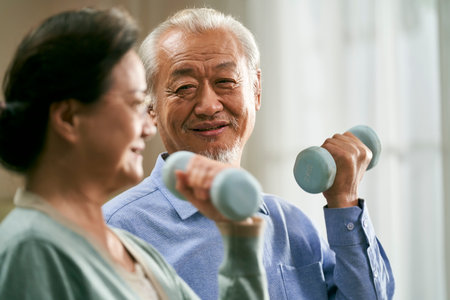 happy senior asian couple exercising at home using dumbbellsの写真素材