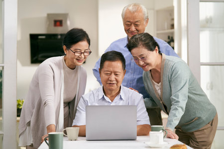 two happy asian couples using laptop computer together at home