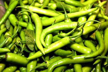 Green chilis scattered at display selling in public marketの写真素材