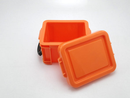 Small plastic orange storage box with lid on top and locks on sides use to put tiny items