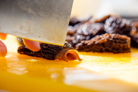 Close-up of a man's hand cutting fresh morel mushrooms.