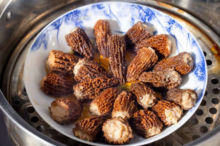 Fresh morel mushrooms are cooked in a pot in the kitchen.の写真素材