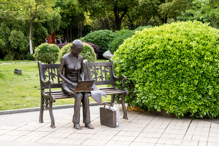 a statue of a girl seat on a benchのeditorial素材