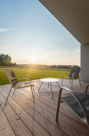 Simple outdoor furniture set standing on a modern patio, beautiful landscape viewの写真素材