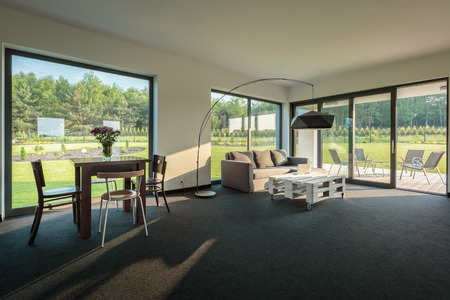 Simple living and dining room combination, spacious interior with window wall systemの写真素材