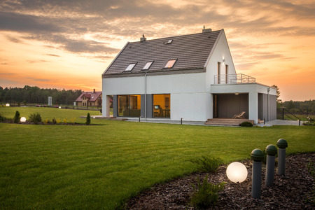 White new design villa with wide green garden and decorative outdoor lightingの写真素材