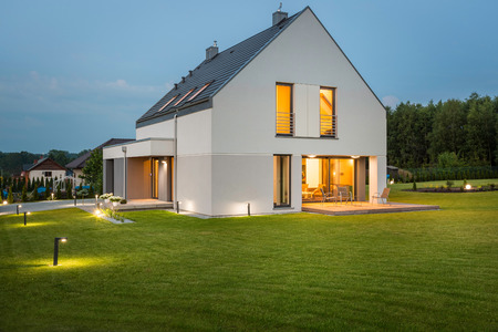 Big light house in new design with wide lawn and outdoor lighting, night viewの写真素材