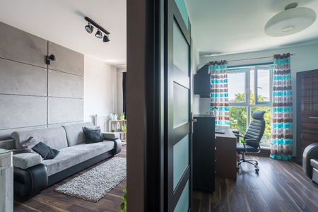 View of a new style flat with light living room and dark brown officeの写真素材