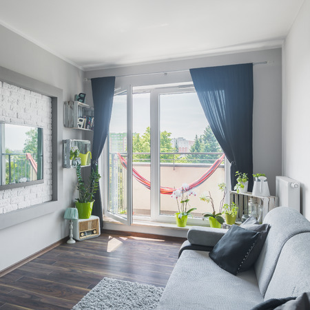 Beautiful living room interior with sofa, big tv, decorative walls, wooden floor and balconyの写真素材