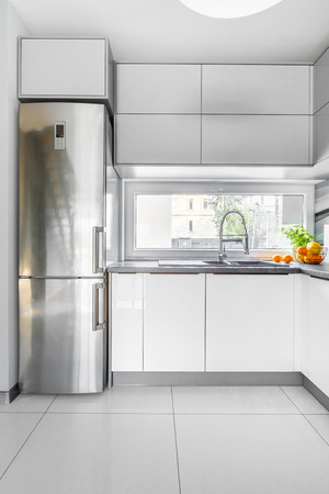 White and spacious kitchen interior with high gloss flooring and windowの写真素材