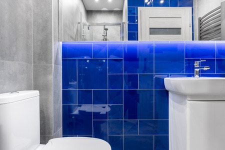 New bathroom with basin cabinet, toilet, shower, mirror and tiling in grey and blueの写真素材