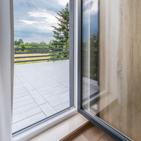 Open balcony doors, large balcony with stylish flooring, simple balustrade and beautiful viewの写真素材