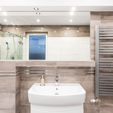 Beige bathroom with washbasin, mirror, shower and stylish radiatorの写真素材