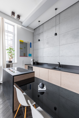 Modern kitchen with black countertops, table and white chairの写真素材