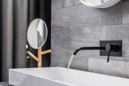 Modern white washbasin with black tap mounted to wallの写真素材
