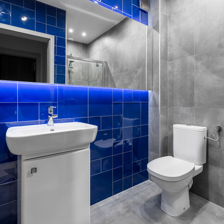New functional bathroom with trendy blue and grey tiling, mirror, basin and toiletの写真素材