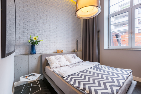 Bright bedroom with window, double bed and brick wallの写真素材