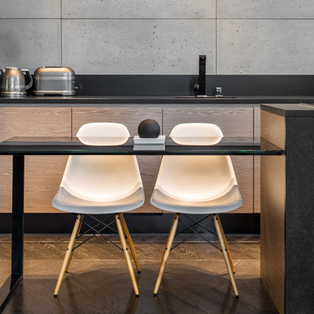 Kitchen table, two white chairs and grey wall tilesの写真素材