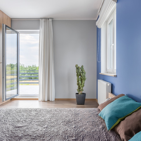 Bright bedroom with large bed and open balcony doorsの写真素材