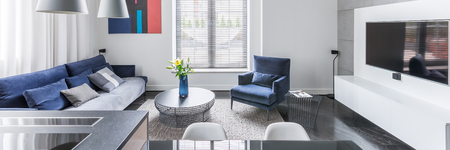 White tv living room with blue upholstered furniture, panoramaの写真素材