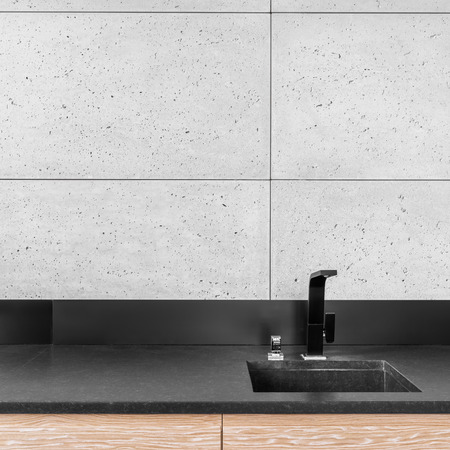 Modern kitchen with grey wall tiles, black worktop, sink and tapの写真素材