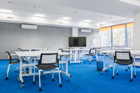 Modern group study room in white and blue with desks, chairs and big screenの写真素材