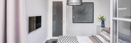 Bright bedroom with tv, painting, double bed and open window, panoramaの写真素材
