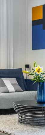 Vertical panorama of cozy living room with sofa and openwork coffee table with flowers in vaseの写真素材