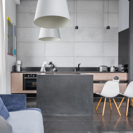 Modern design kitchen with island, table with white chairs and grey tiles on wallの写真素材