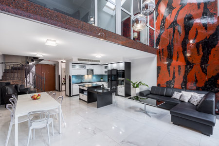 Stylish open living room with designed chairs, leather sofa and red and black wall tiles