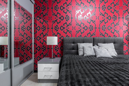 Cosy bedroom with big bed and patterned black and red wallの写真素材