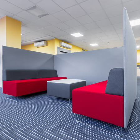 University lounge area with red sofa, table and grey partitionの写真素材