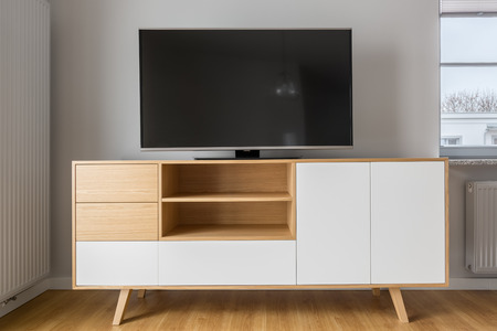 Big tv screen on stylish white and wood cabinetの写真素材