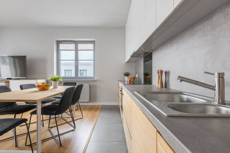 Stylish kitchen with long countertop and dining room in modern apartmentの写真素材