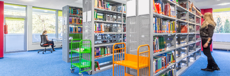 Panoramic view of light library interior with modern shelves and colorful trolleyの写真素材