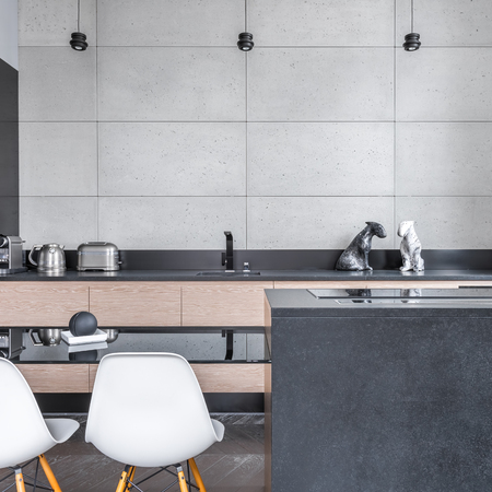 Modern kitchen with black table, white chairs, and grey tilingの写真素材