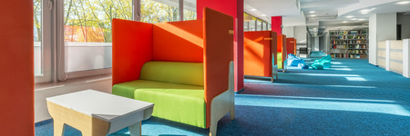 Panorama of library lounge area with green sofas and red partitionsの写真素材