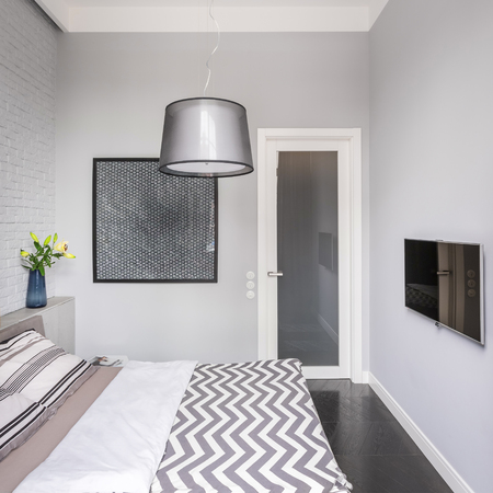 Bright bedroom with tv, double bed and stylish lampの写真素材